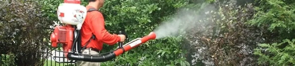 Mosquito control technician fogging shrubs and landscaping for mosquito treatment in Anchorage, AK